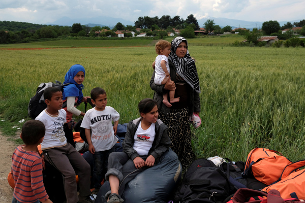 People wait to board a bus as they are transferred to a different location, at a makeshift camp for refugees and migrants at the Greek border village of Idomeni, on Monday (Reuters photo)
